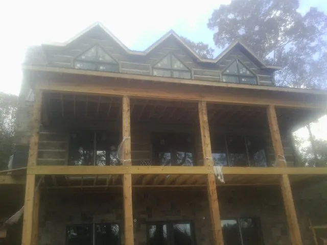 Dormers and porch framing on a large log home under construction — Roof Coating work by our crew in Oak Ridge
