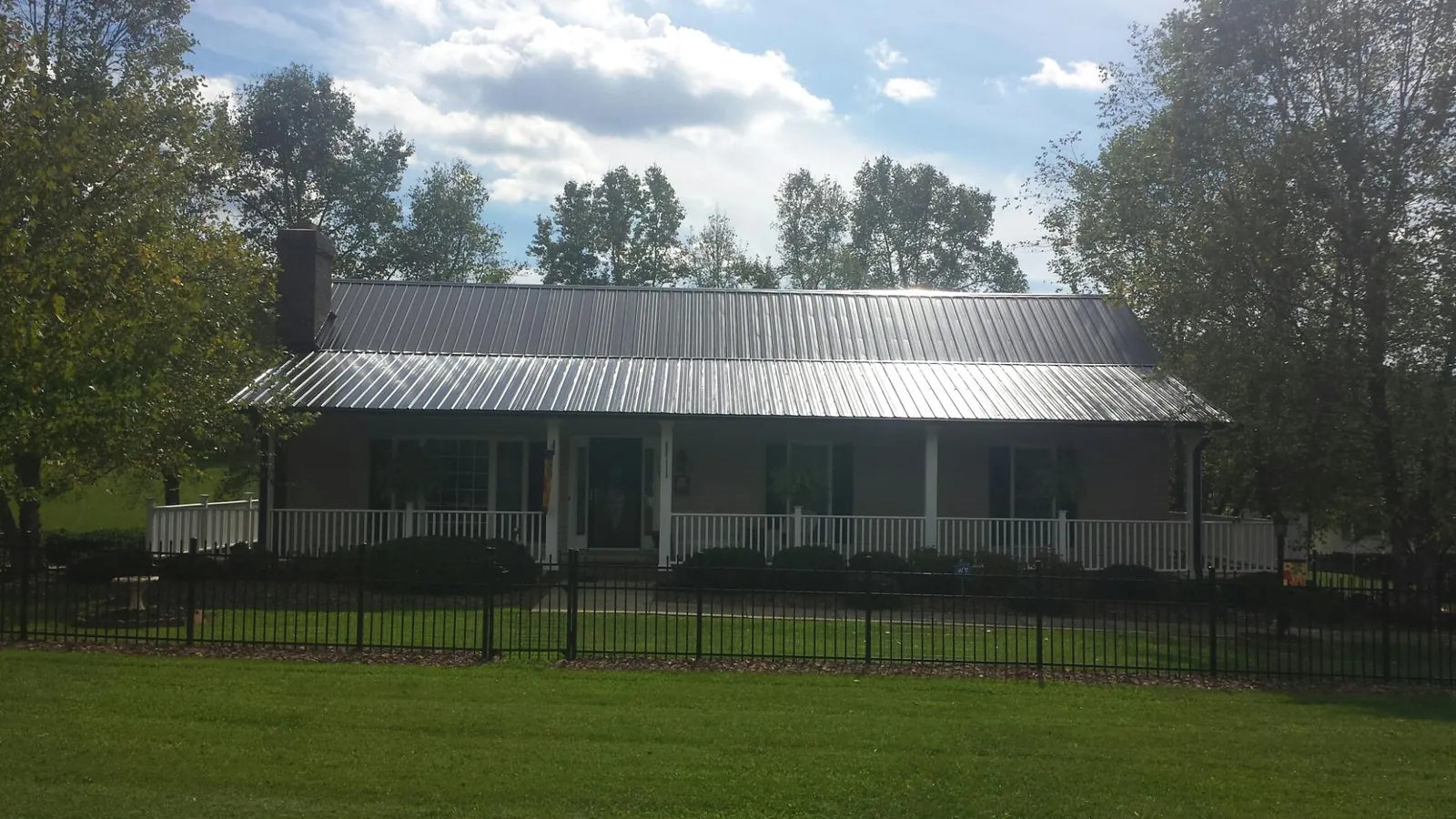Gray metal roof on a brick ranch with a full width front porch — Gutter Guard Installation work by our crew in Oak Ridge