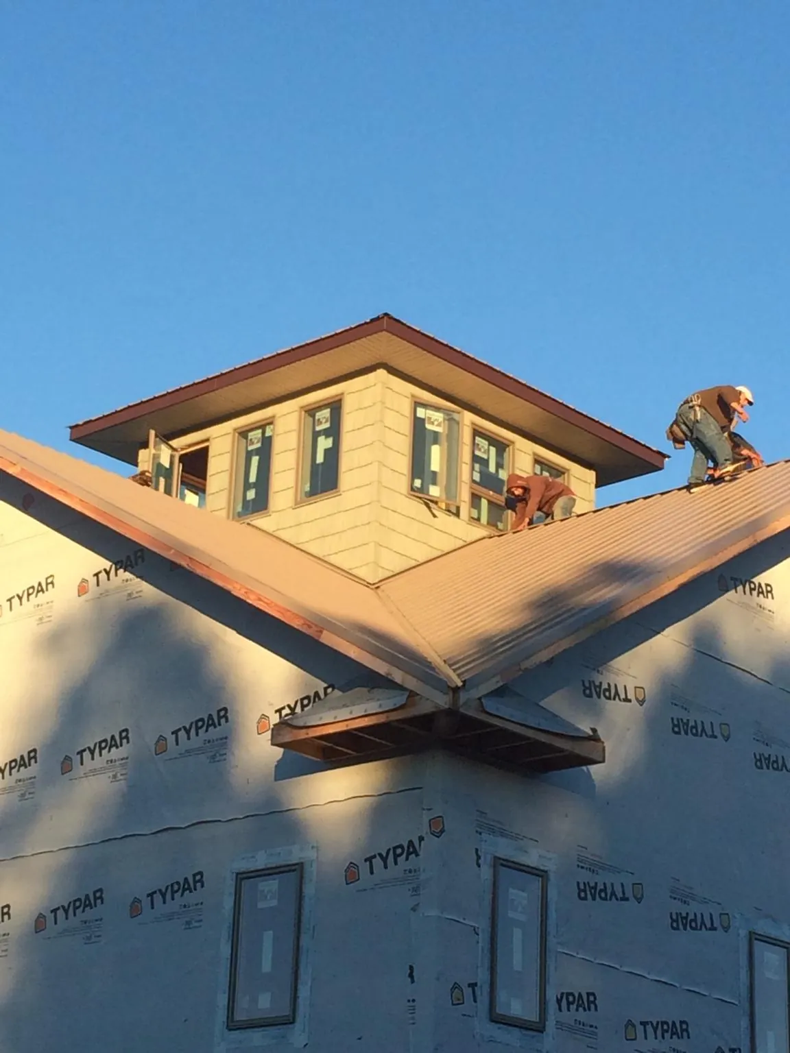 Roofers working around a rooftop cupola on a new metal roof at sunset — Roof Waterproofing in Oak Ridge by Roofing Brothers